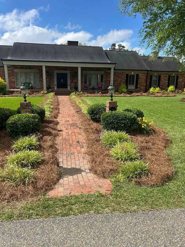 Pine straw beds lining a brick front walk