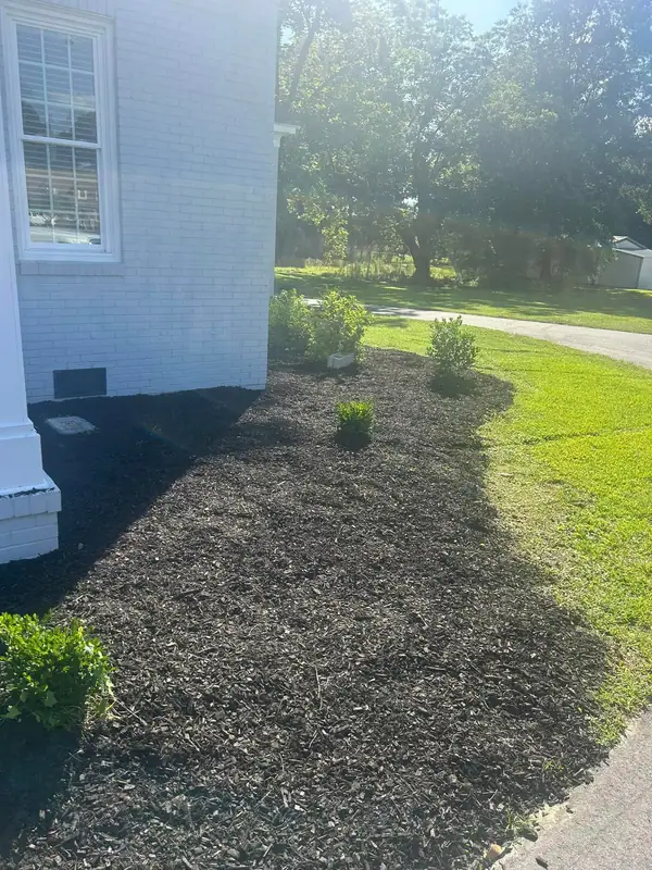 Fresh black mulch bed along the corner of a white house