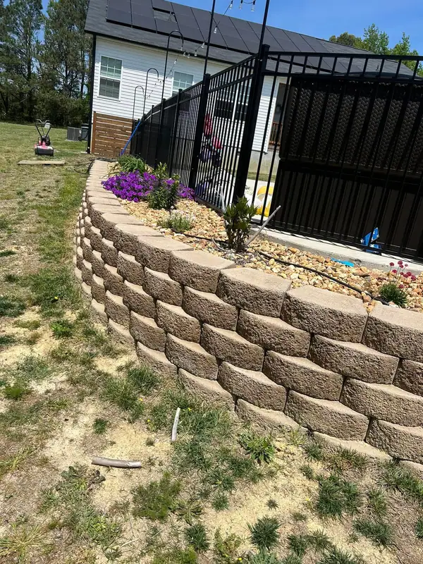 Block retaining wall with a river rock bed and flowers