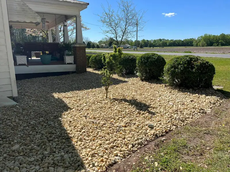 River rock bed and shrubs along a country porch