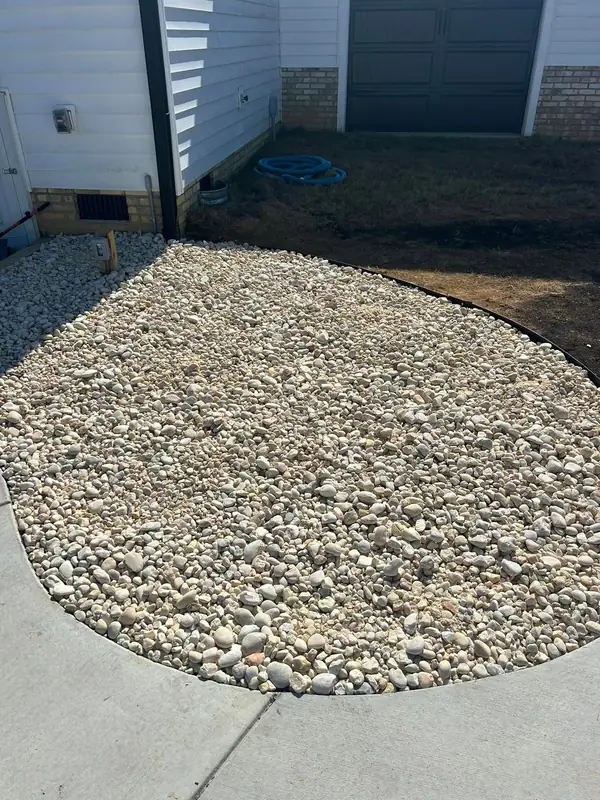 Rounded river rock bed beside a garage walk