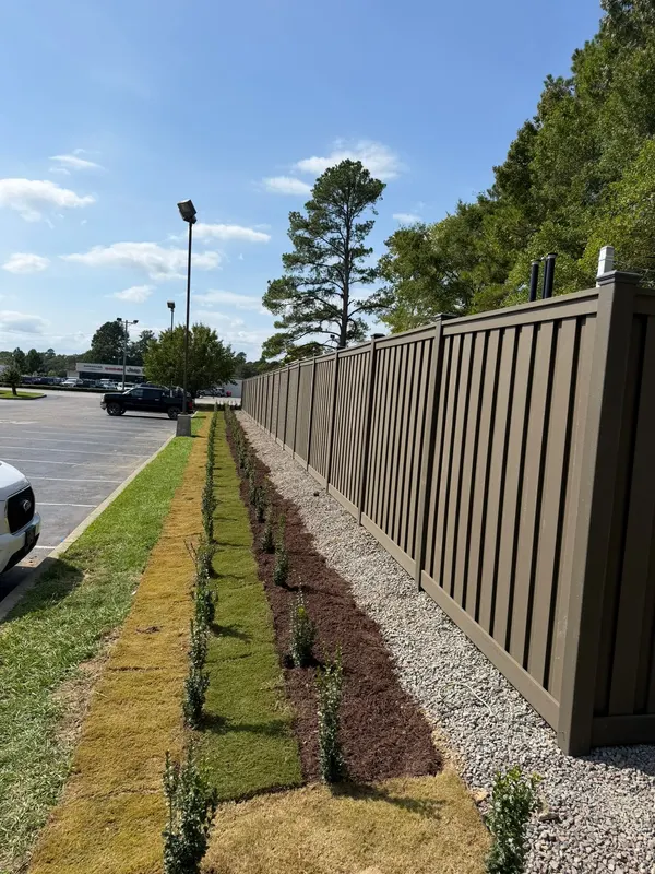 Fresh sod laid in a strip beside a new planted bed along a fence